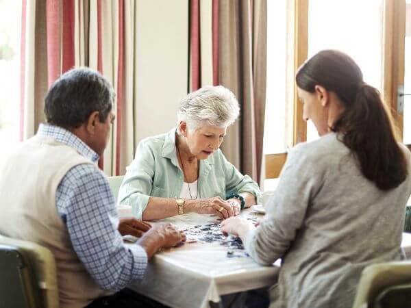 Due persone anziane sedute a tavola durante una visita psicologica